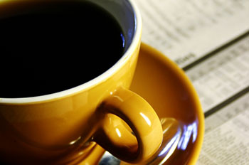 a cup of black coffee set on a newspaper