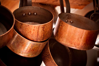 copper saucepans hanging from an overhead storage rack
