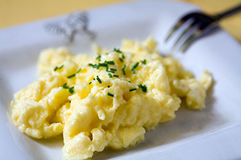 a plate of scrambled eggs garnished with chopped chives