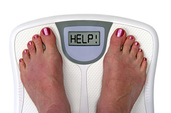 top view of two bare feet standing on a personal scale that reads 'HELP' instead of a number