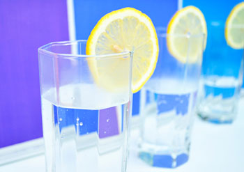 a clear water glass filled with water and garnished with a slice of lemon