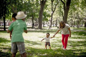 a family of two adults and two children play in a wooded park area