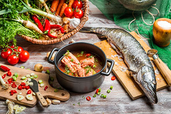 some elements of a Mediterranean-style diet, including fish, vegetables, fruits, and olive oil, being used to make a fish soup