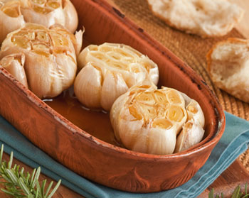 several heads of roasted garlic in a garlic roaster