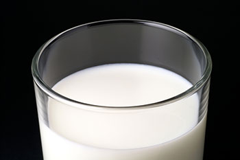 a glass of milk in a clear glass against a dark background