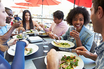 A group of friends dining at a restaurant at a table outdoors