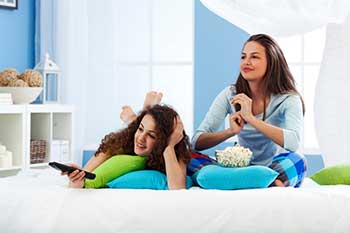 A pair of female adolescents who appear to be watching television