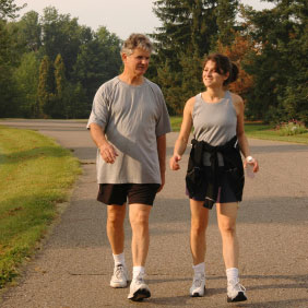 two adult persons, dressed for exercising, walking on a paved track in the outdoors