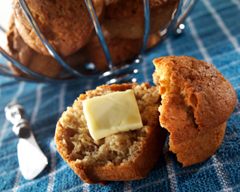 a banana nut muffin sliced in half with a pat of butter or margarine on it