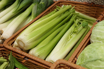 bunches of fresh celery in baskets at a farmers' market