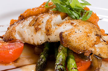 a filet of halibut on a bed of asparagus and tomatoes