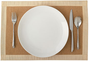 a standard place setting of fork, dinner plate, knife, and spoon