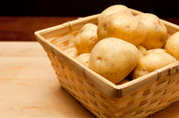 a square basket containing several Yukon Gold (yellow) potatoes