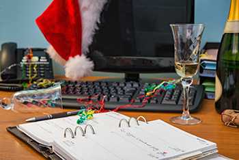 An office desk with computer during a holiday party - with Santa hat and a glass of champagne on the desk