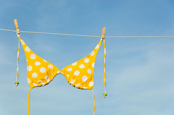 A yellow polka-dot bikini top hanging on a clothesline