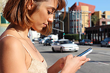 a woman in an urban setting using her smart phone for texting