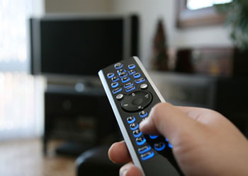 a hand holding a television remote pointed at the television