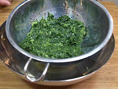 Place the thawed spinach in a strainer and place the strainer in a bowl.
