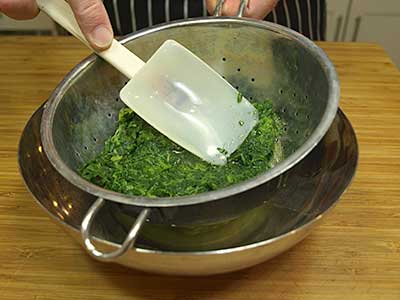 Using the back of a rubber spatula or a spoon press the excess water out of the spinach.