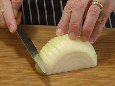 Place the onion on a cutting board cut side down. Slice on an angle to cut a wedge from the onion.