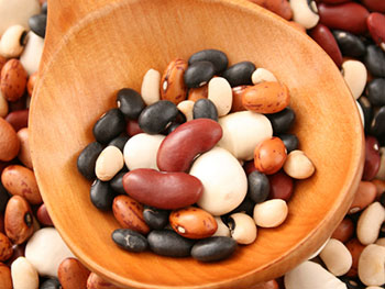 a wooden spoon full of a variety of dried beans