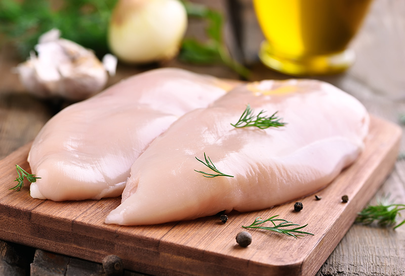Raw chicken breasts on a wooden cutting board