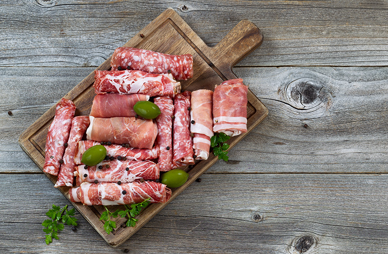 a wooden platter of cured deli meats