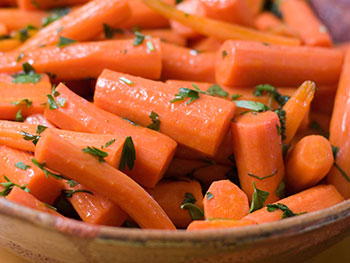glazed baby carrots in an earthenware bowl