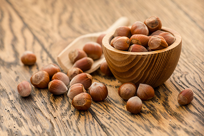 a wooden bowl full of unshelled hazelnuts, one of the 'big eight' food allergies