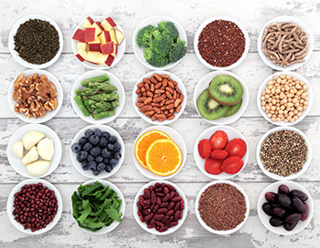 a variety of healthy ingredients, including vegetables, fruit, legumes, and grains, displayed individually in small bowls