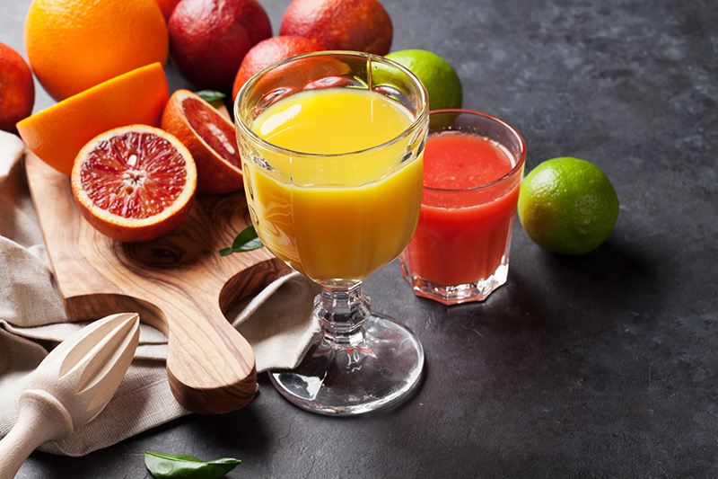 glasses of fruit juice and various types of citrus fruit