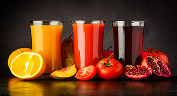 3 glasses of fruit juice: orange, tomato, and pomegranate