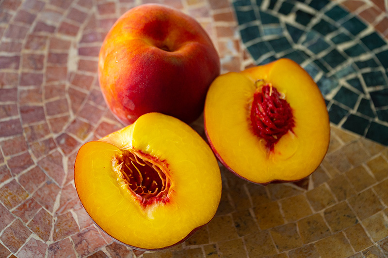 whole and sliced peaches showing the pits inside the peach