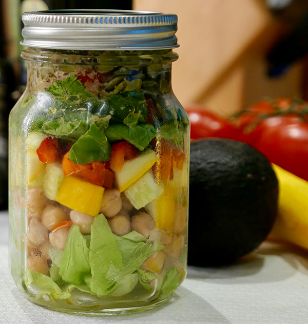 salad in a jar, with yellow squash, red bell pepper, lettuce, garbanzo beans, and dressing