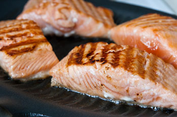 filets of salmon roasting on a grill pan