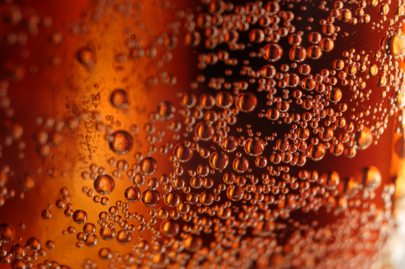 bubbles on the side of a glass of brown soda
