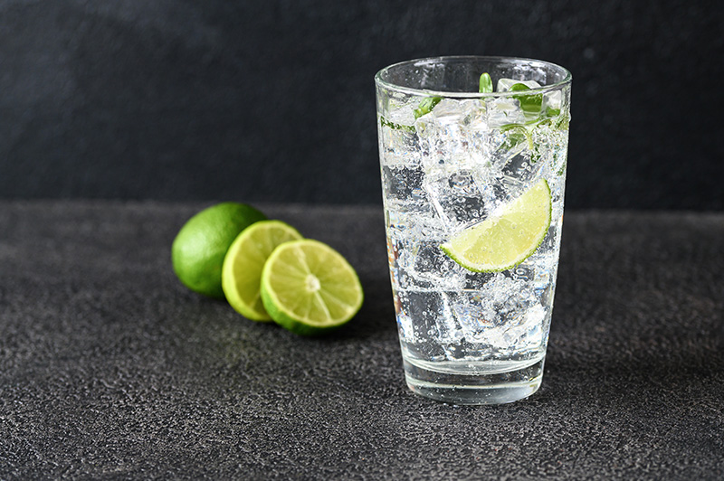 a clear glass of sparkling water garnished with lime slices