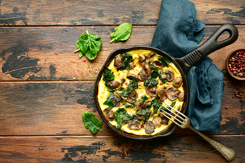 a spinach and mushroom frittata made in an iron skillet