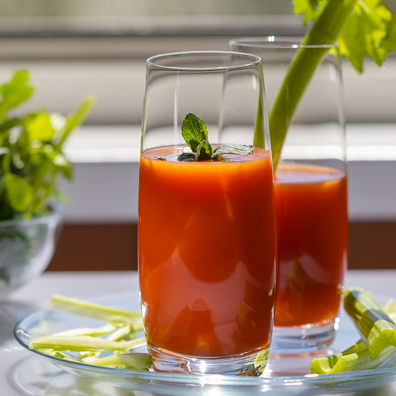a glass of tomato juice garnished with a rib of fresh celery