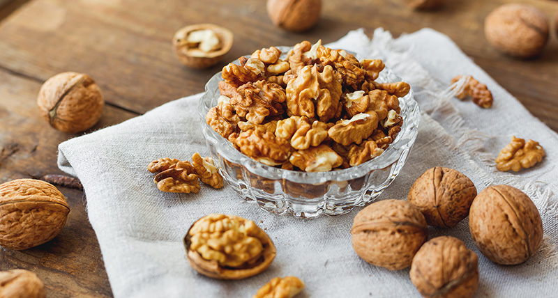 Walnuts, both whole and shelled, in a glass bowl. Walnuts are high in iron.
