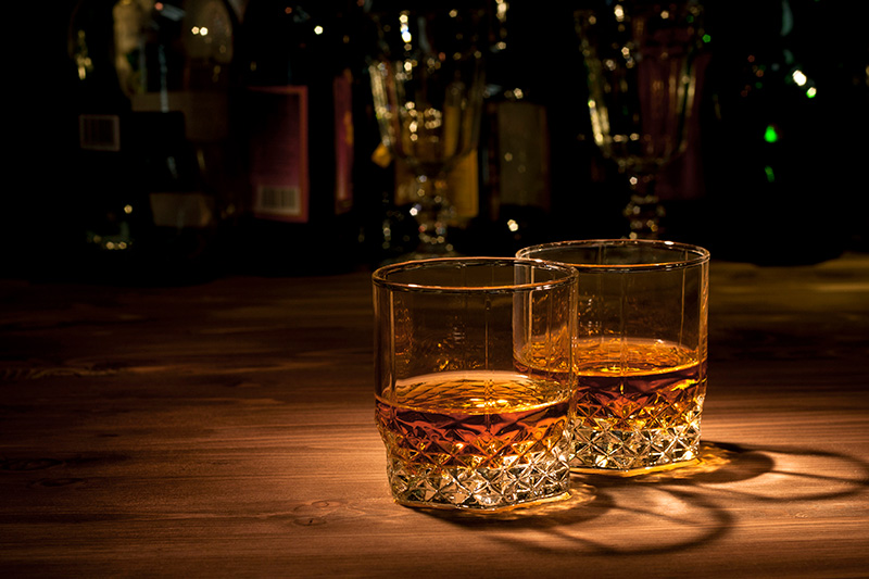 two highball glasses of whiskey on a bar