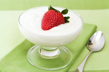 a dish of yogurt garnished with a strawberry