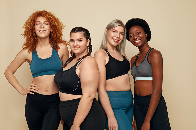 four female-presenting persons of various ethnicities and body sizes, wearing activewear