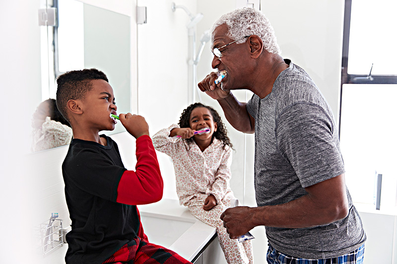 a grandfather teaching his grandchildren how to brush their teeth