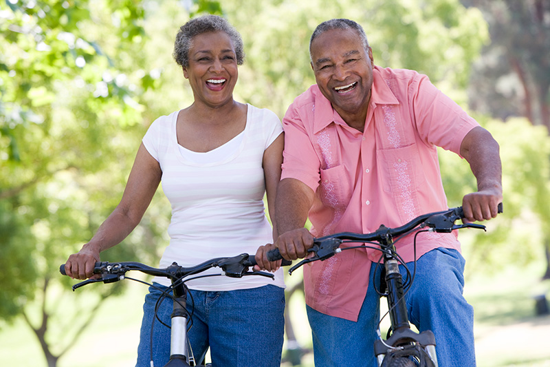 a middle-aged African-American couple, both on bicycles
