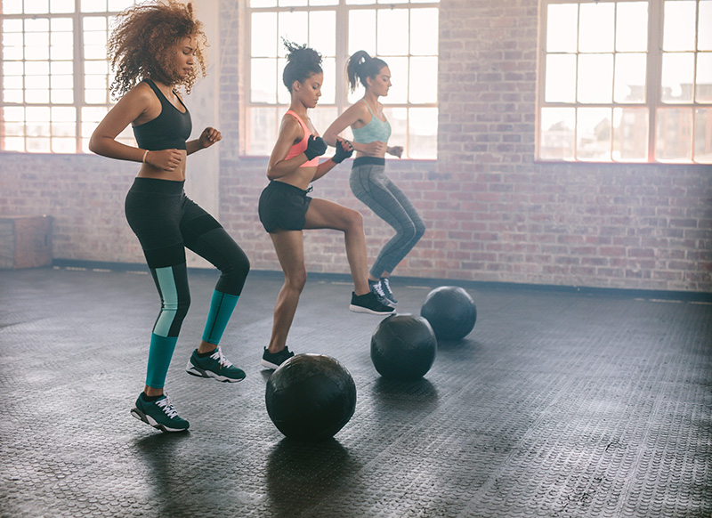 three women participating in an exercise class using medicine balls