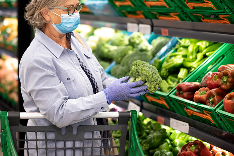 Older woman at a grocery store selecting broccoli
