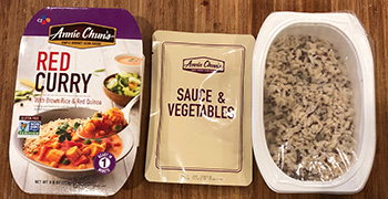 The package contents for Annie Chun's shelf-stable Red Curry with Brown Rice & Red Quinoa: box, sauce and vegetable packet, and dish of rice and quinoa.